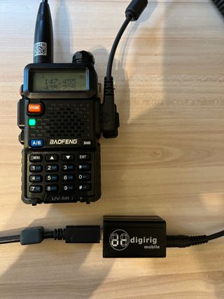 A baofeng uv-5r handheld ham radio connected to a digirig interface.